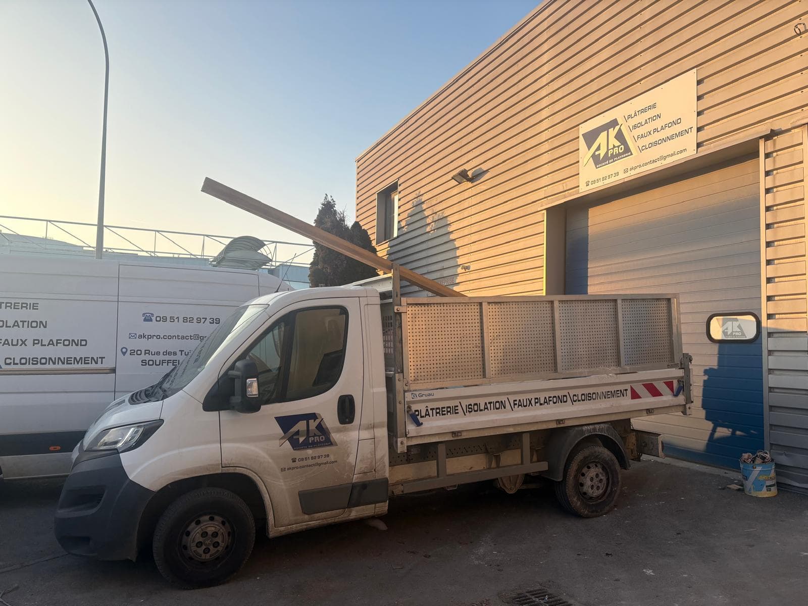 Camion benne AK Pro marqué, chargé de matériaux devant le dépôt