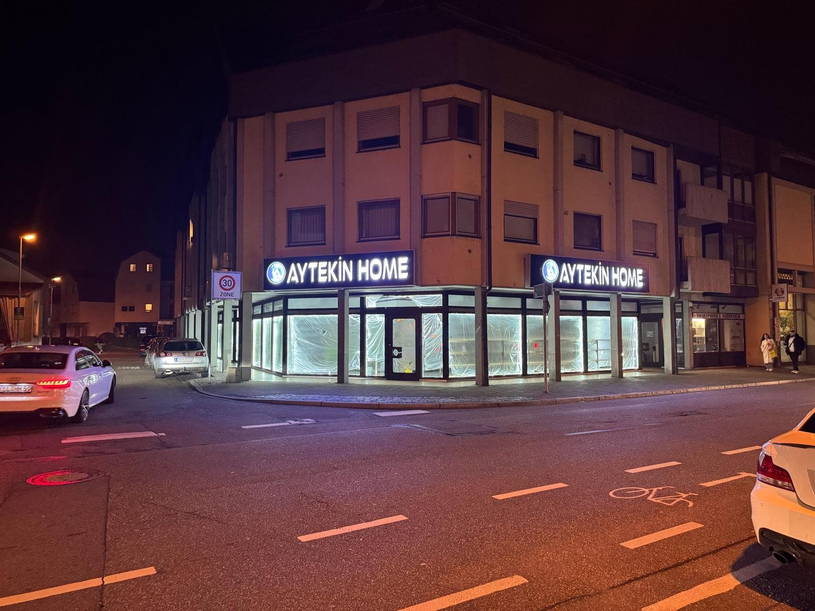 Enseigne Aytekin Home allumée à l'angle du bâtiment, de nuit