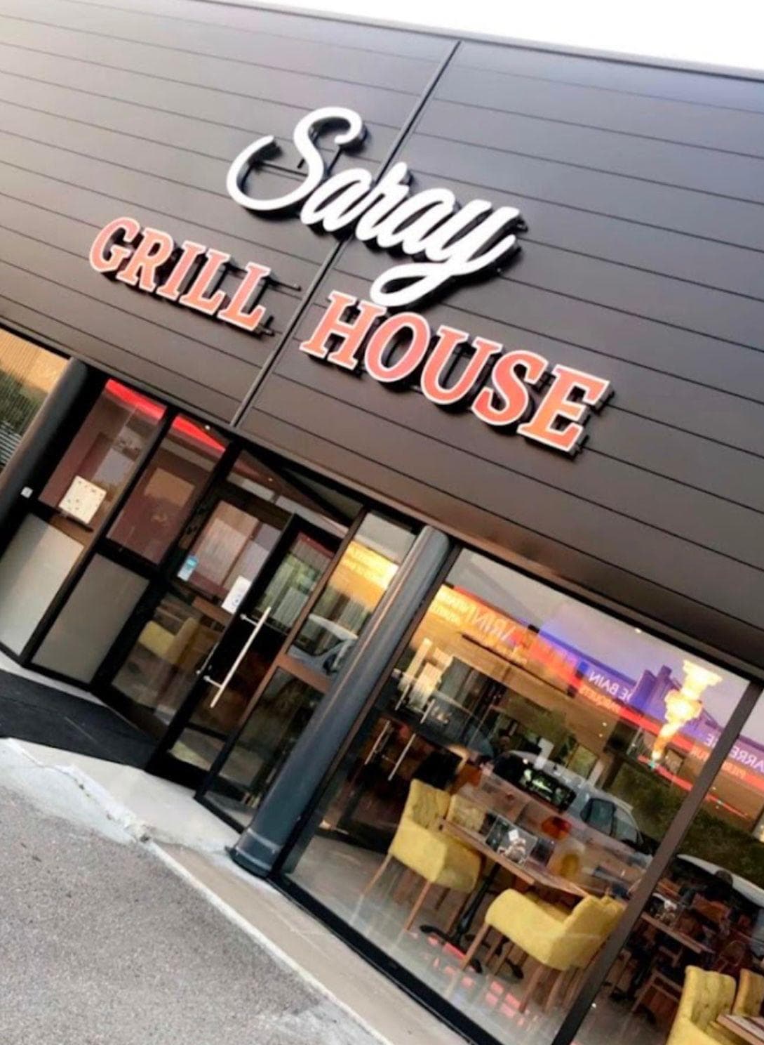 Enseigne blanche rétroéclairée Saray Grill House au-dessus de la vitrine
